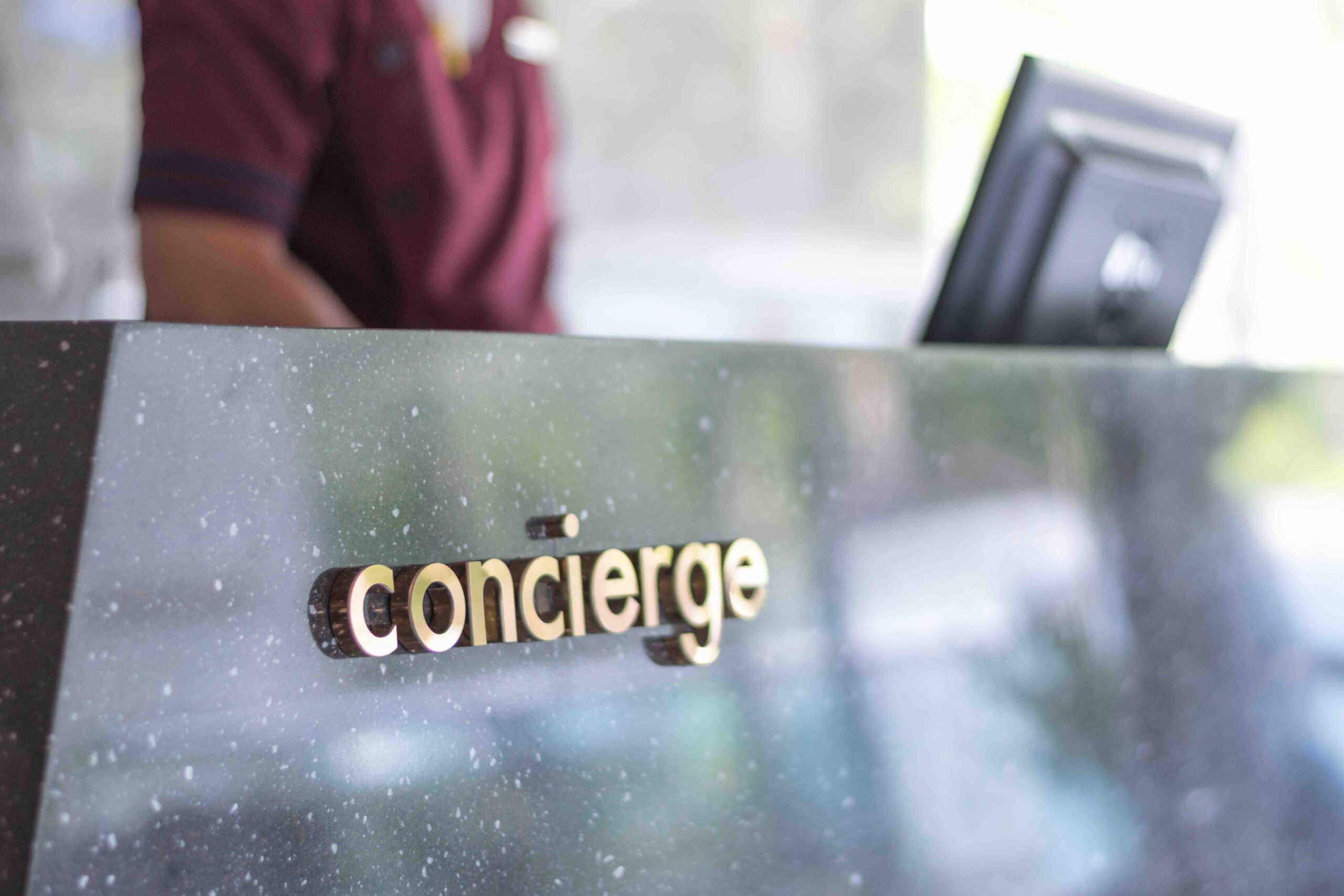 concierge service desk counter with happy employee staff receptionist working in front of hotel with tourist guest business customer.